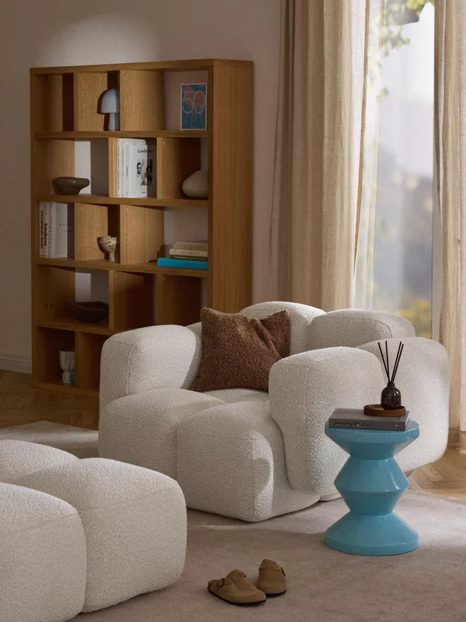 Modern beyaz peluş koltuk ve kahverengi yastık ile dekoratif ahşap raf ve mavi sehpa