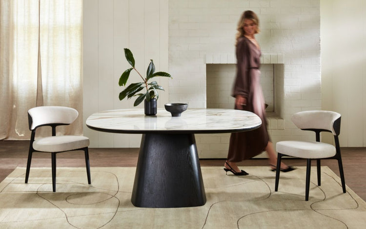 Minimalist tasarımlı siyah ayaklı mermer yemek masası ve krem renkli sandalyeler ile modern oturma alanı