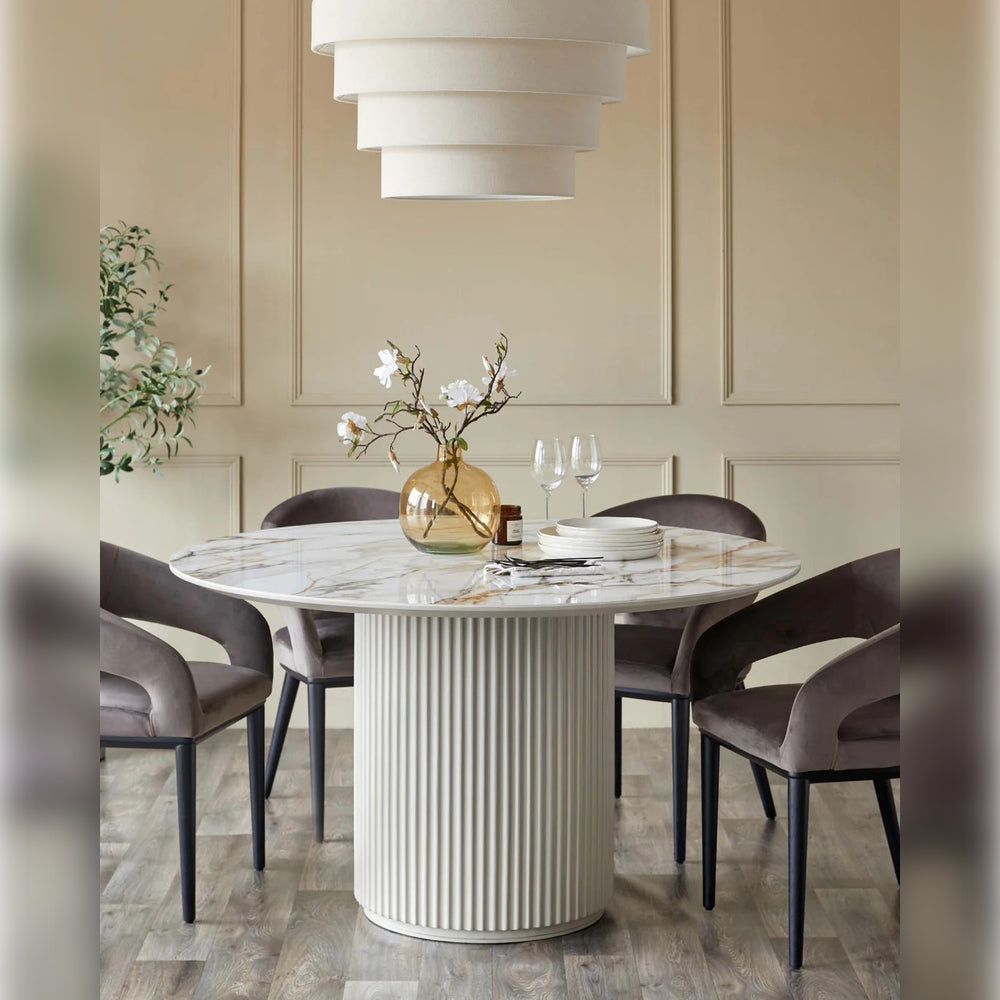 Minimalist beyaz masa etrafında siyah sandalyeler ve üzerinde çiçekli dekoratif vazo